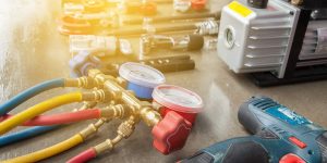 A collection of electrical tools and equipment, including pliers, wire strippers, and a multimeter, are spread out on a work surface.