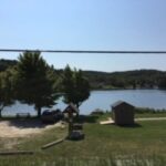 A scenic view of a lake with trees and a small building on the shore.