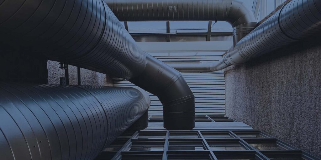 A network of large industrial pipes and ducts fill a confined space.