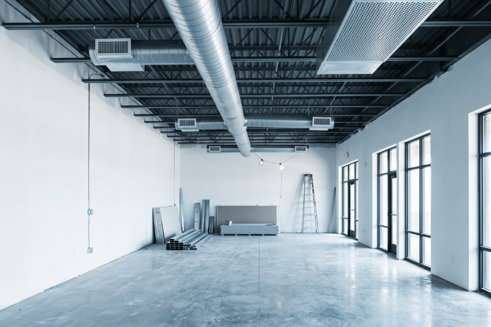 Commercial tenant fit-out interior under construction showing exposed HVAC ductwork and supply diffusers